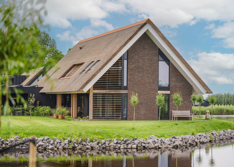 Vrijstaande woning met rieten dak, hoge ramen en tuin aan het water