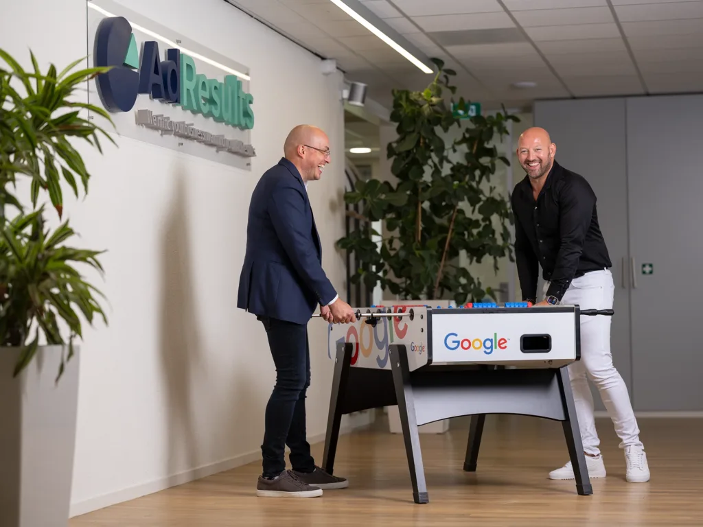 Twee collega's spelen en lachen bij een tafelvoetbalspel