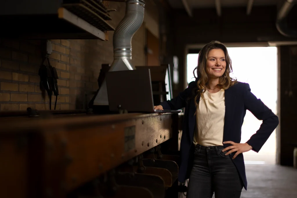Brunette kijkt lachend weg, voor haar staat een laptop
