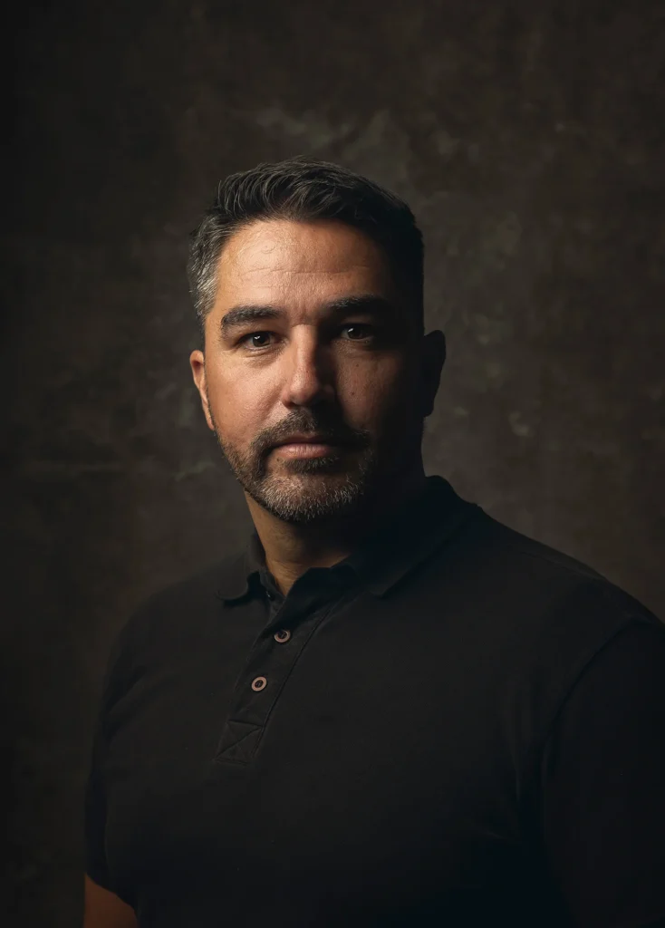 Portret van fotograaf Daniël Wenzel tegen een donkere achtergrond.