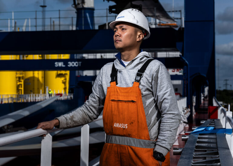 Offshore-mederker-staat-bakboordzijde-kijkend-over-scheepsdek