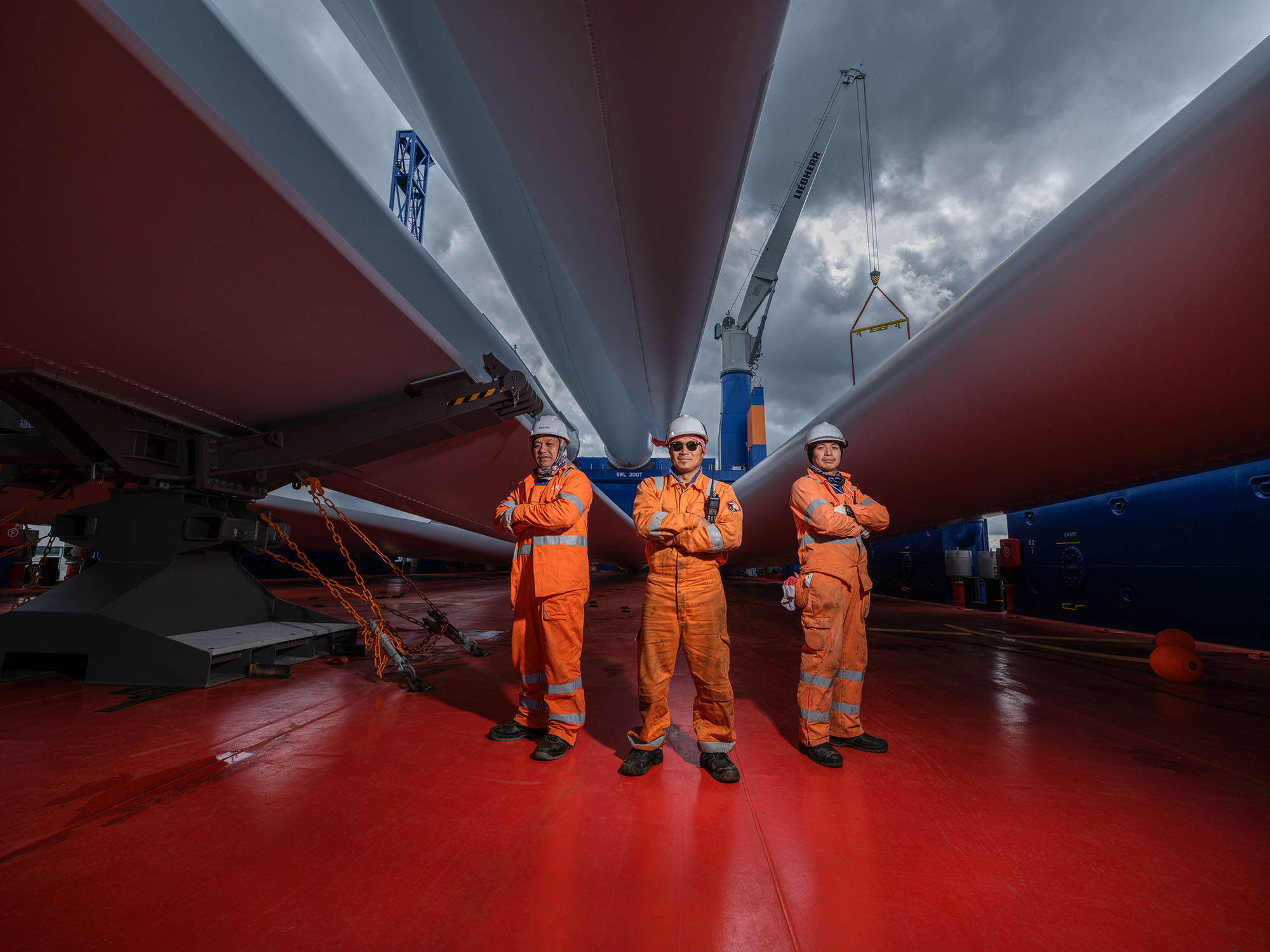 Personeel poseert op dek van schip onder grote onderdelen van windmolen