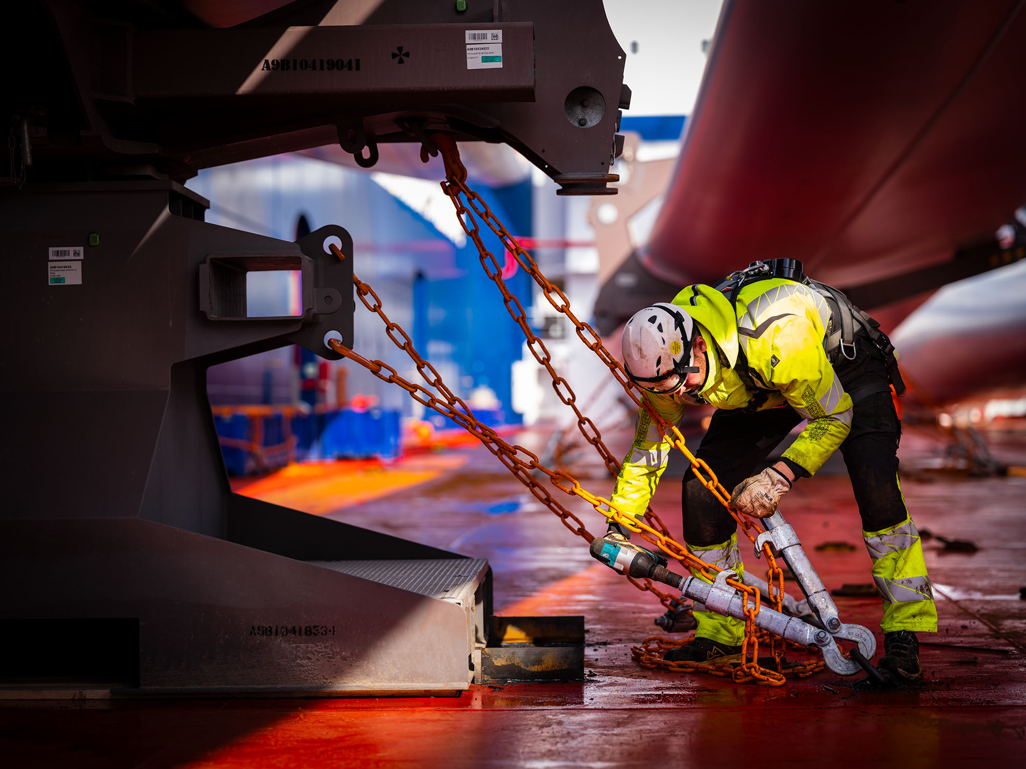 Medewerker in veiligheidskleding zet lading vast met kettingen op een schip