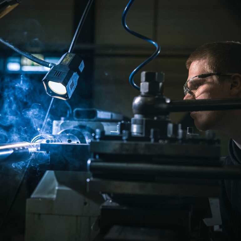 Metaalbewerker bedient een machine in een industriële werkplaats.