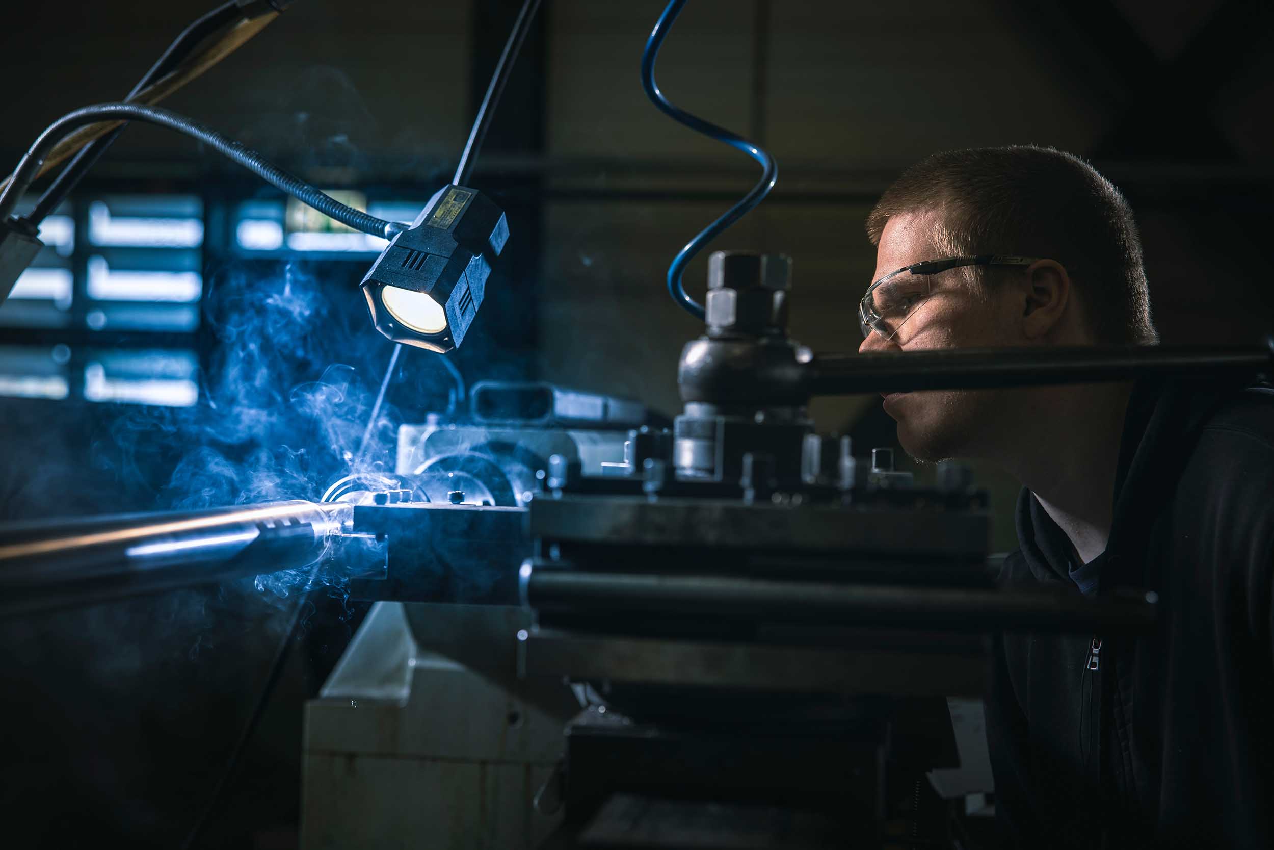 Metaalbewerker bedient een machine in een industriële werkplaats.