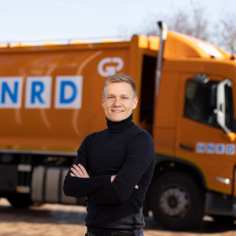 Medewerker NNRD staat voor oranje vuilniswagen