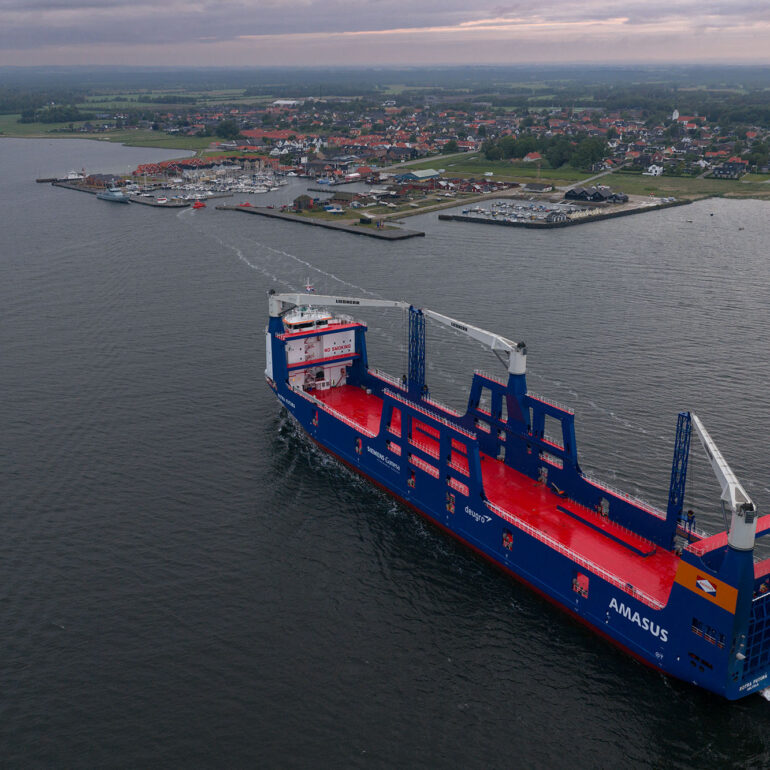 Luchtfoto van een blauw vrachtschip met rood dek en dekkranen op het water