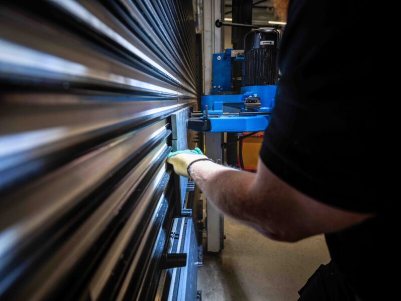 Werkhandschoen van een Panelvision-medewerker bij een plaatbewerkingsmachine.