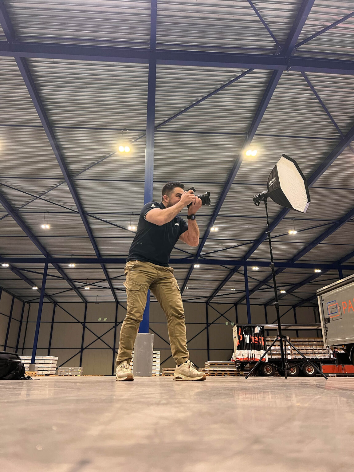 Fotograaf maakt met een camera en een softbox opnamen in een bedrijfshal.